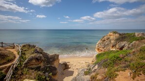A coastal landscape with a sandy beach, rocky outcrops, and a clear blue sky. - Masana Algarve, a Destination by Hyatt (Albufeira)