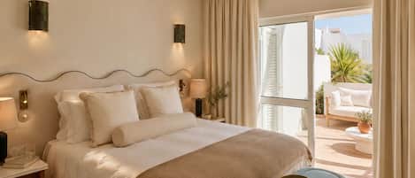 Camera d'albergo con un letto, lampade ai comodini, un comodino, una finestra con tende e vista esterna.