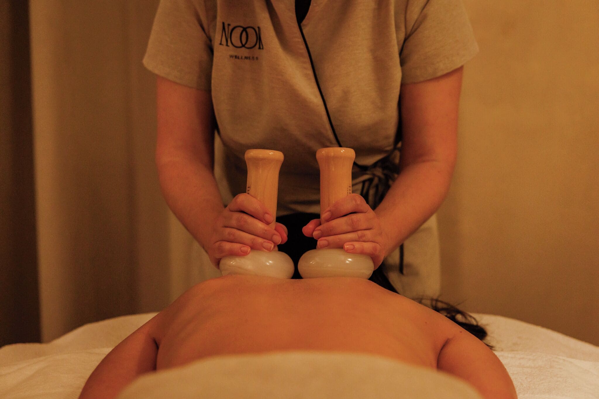 Een persoon ontvangt een massage, waarbij een therapeut een massagewortel gebruikt.