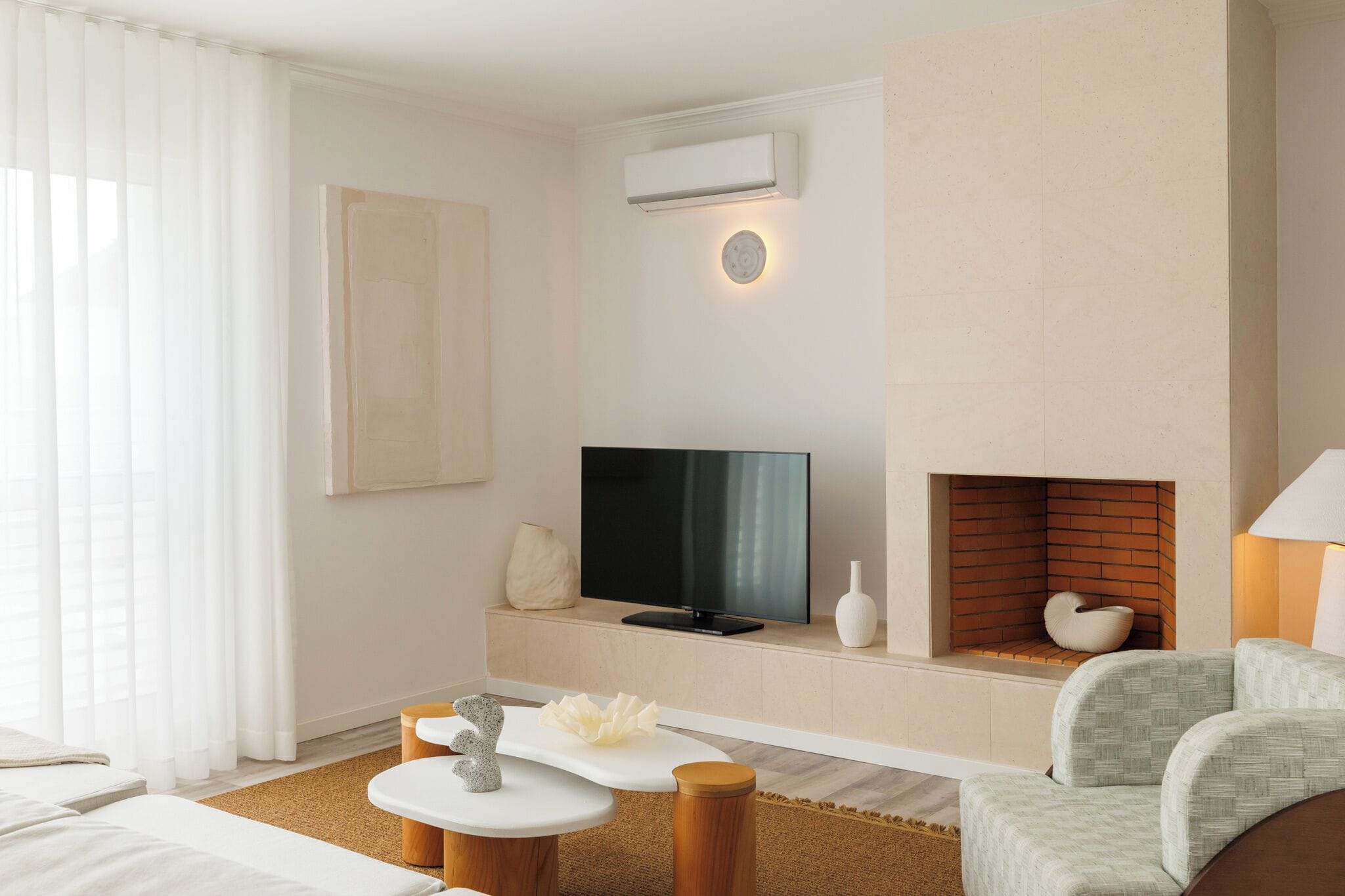 Una habitación de hotel moderna con televisión de pantalla plana, chimenea, sofá y una mesa de centro.
