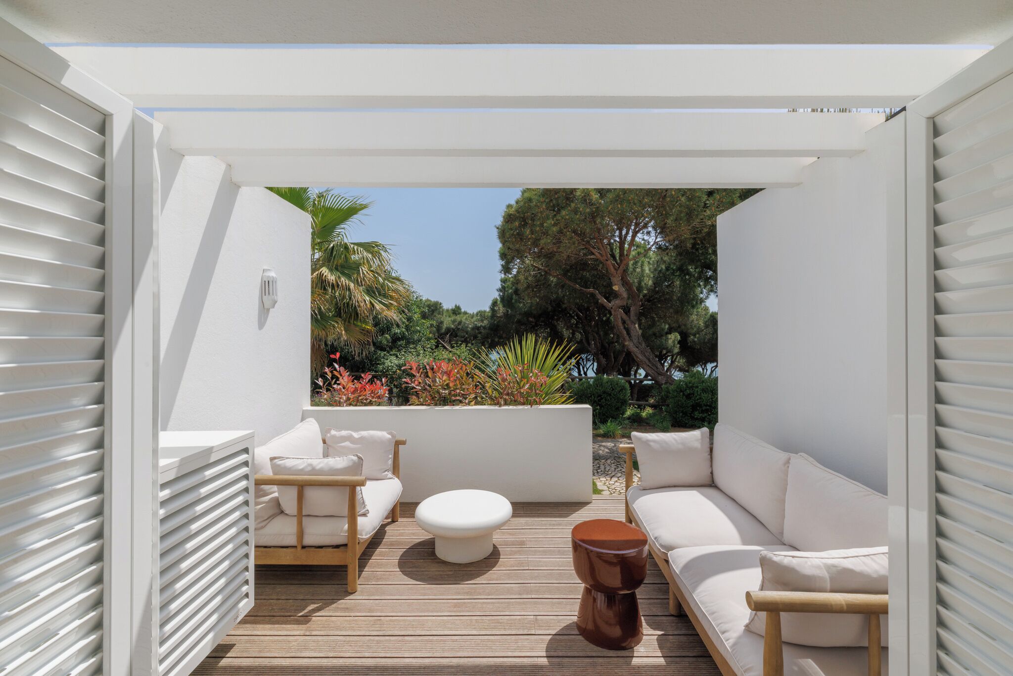An outdoor patio with a white sofa, a round table, and a wooden deck.