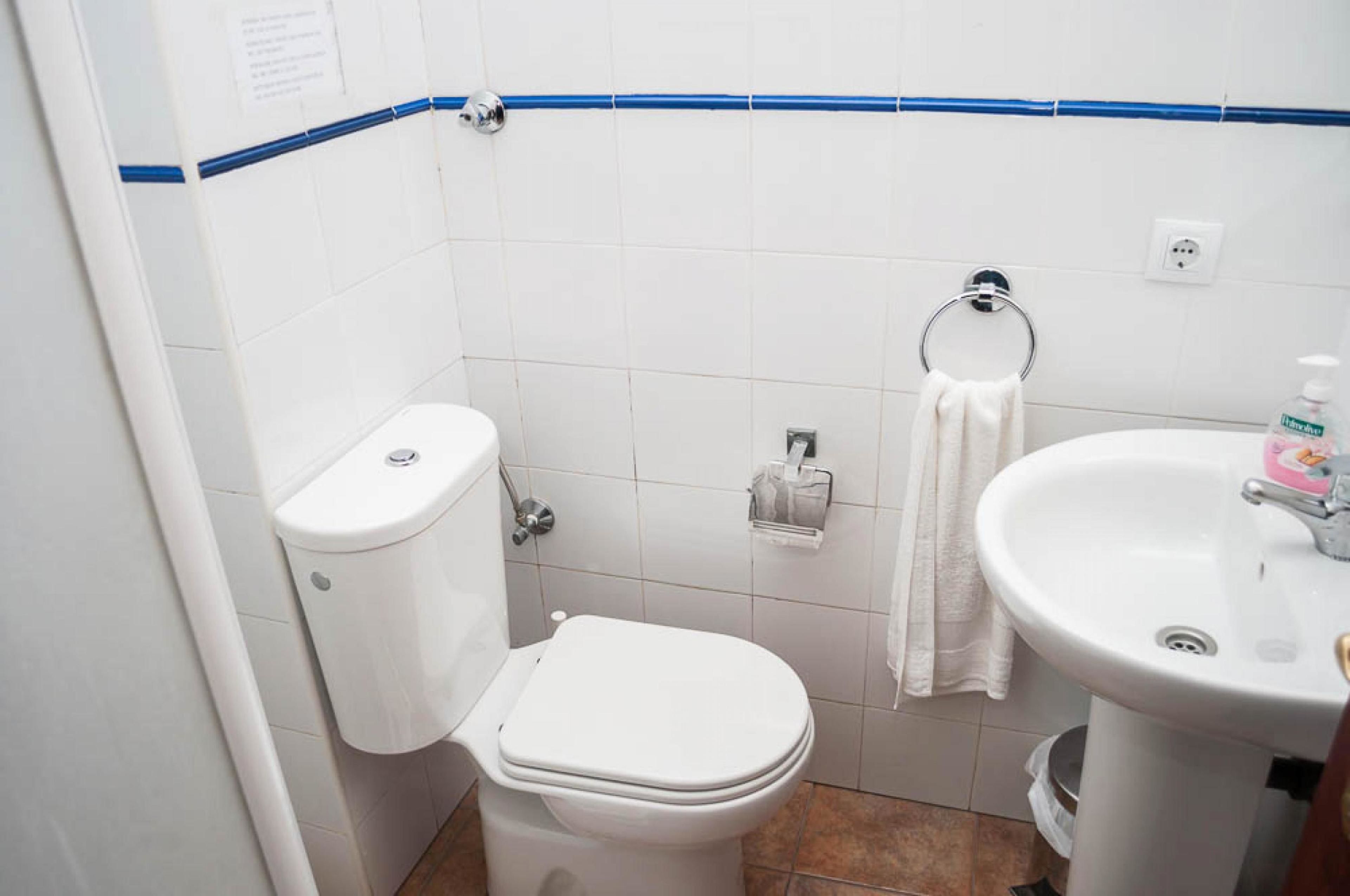 A small, clean bathroom with a toilet, sink, and towel rack.