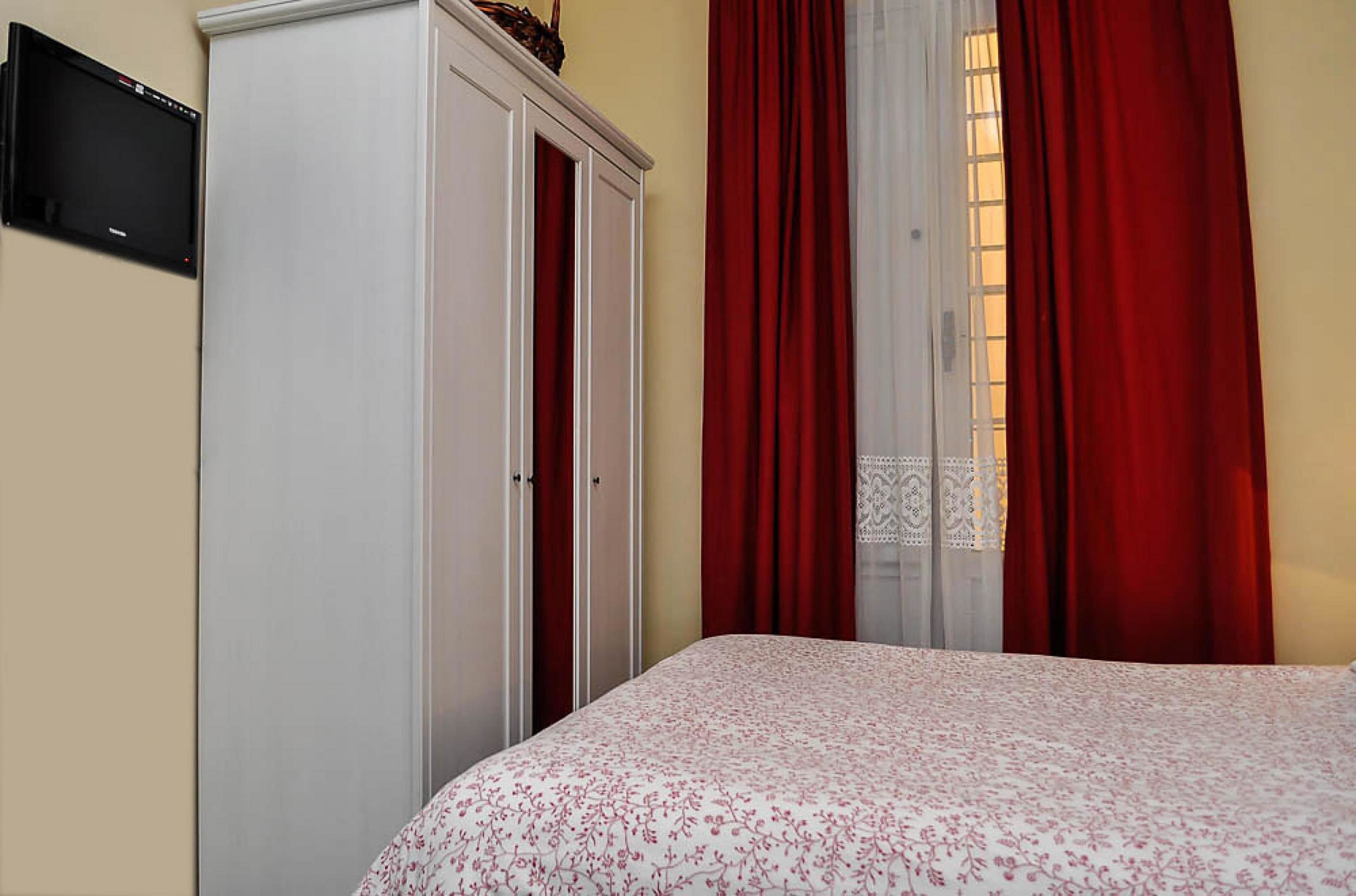 Un dormitorio con cama, armario y televisión en la pared.