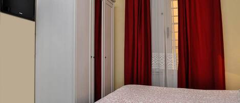 Un dormitorio con cama, armario y televisión en la pared.