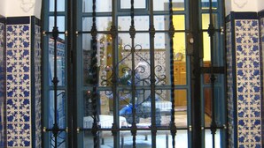 A black metal gate with a glass panel and a year plaque, set in a white and blue patterned wall. - Pensión Montoreña (Seville)