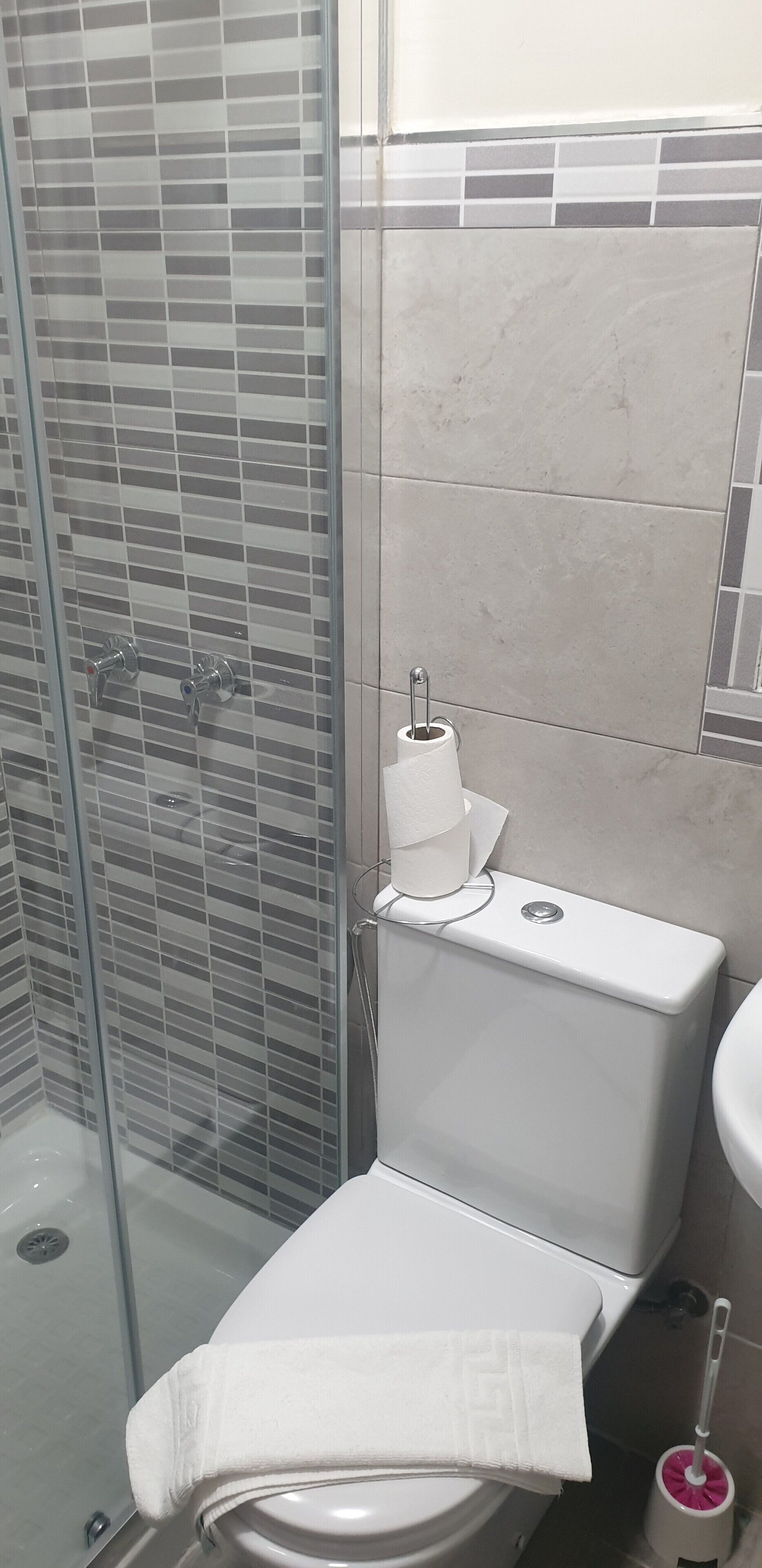 Un baño con cabina de ducha de vidrio, inodoro y lavabo.