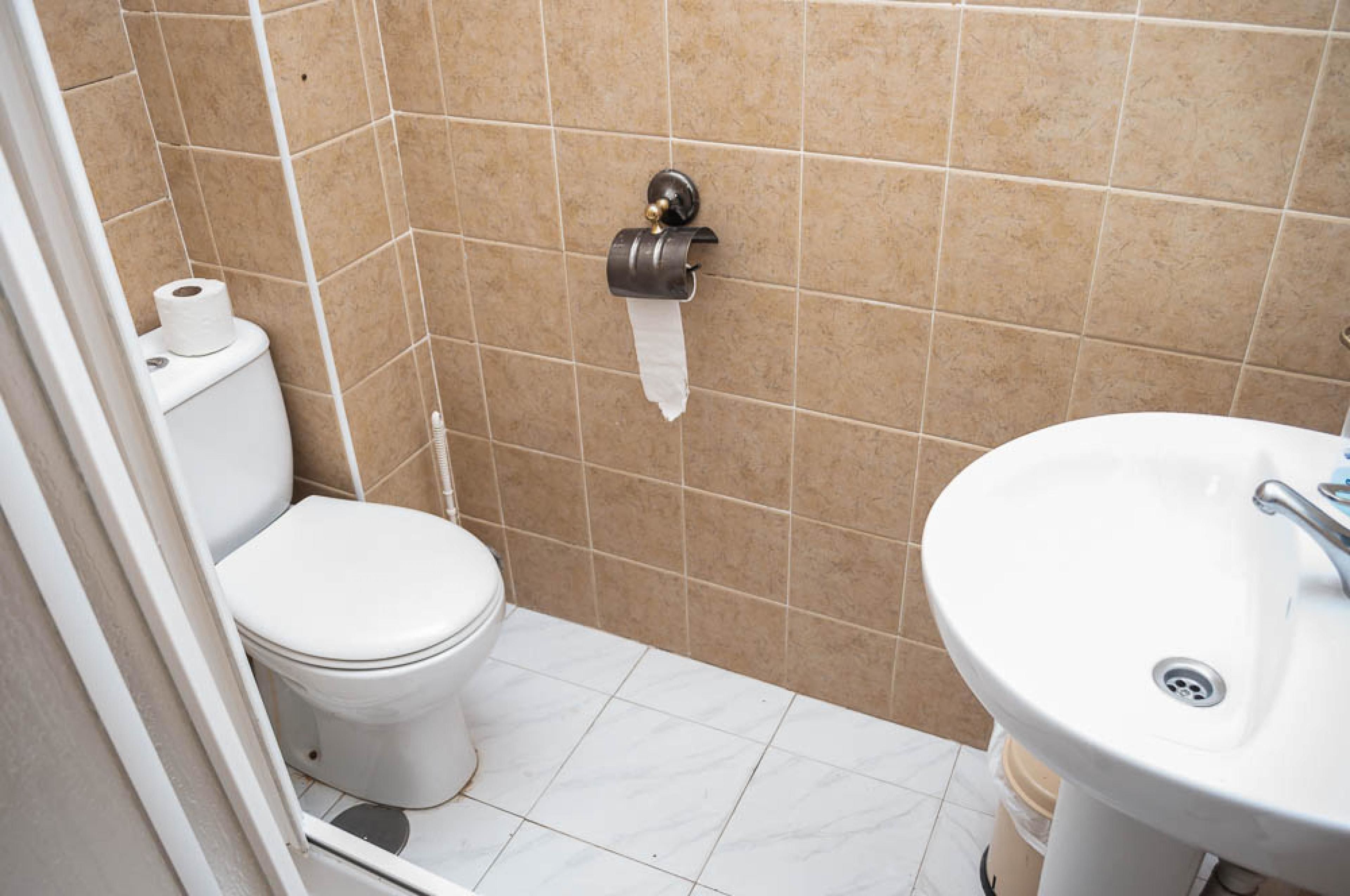 A bathroom with a toilet, a paper towel dispenser, and a sink.