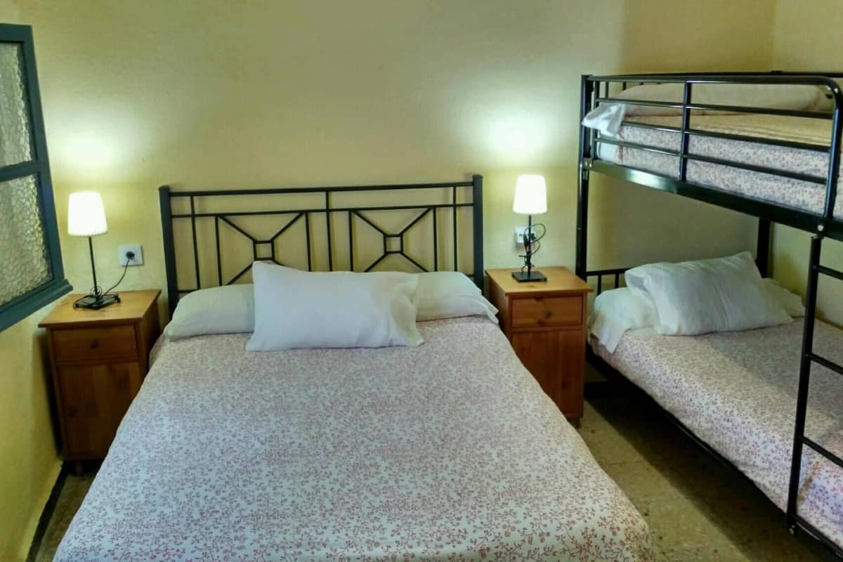 A room with two beds, each with a wooden nightstand and a lamp.