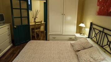 Une chambre à coucher comprenant un lit, un bureau, une chaise, une armoire et une table de chevet avec une lampe.