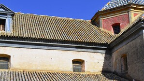 A courtyard with tiled roofs, two striped lounge chairs, and a small table with a bowl and glasses. - Pensión Montoreña (Seville)