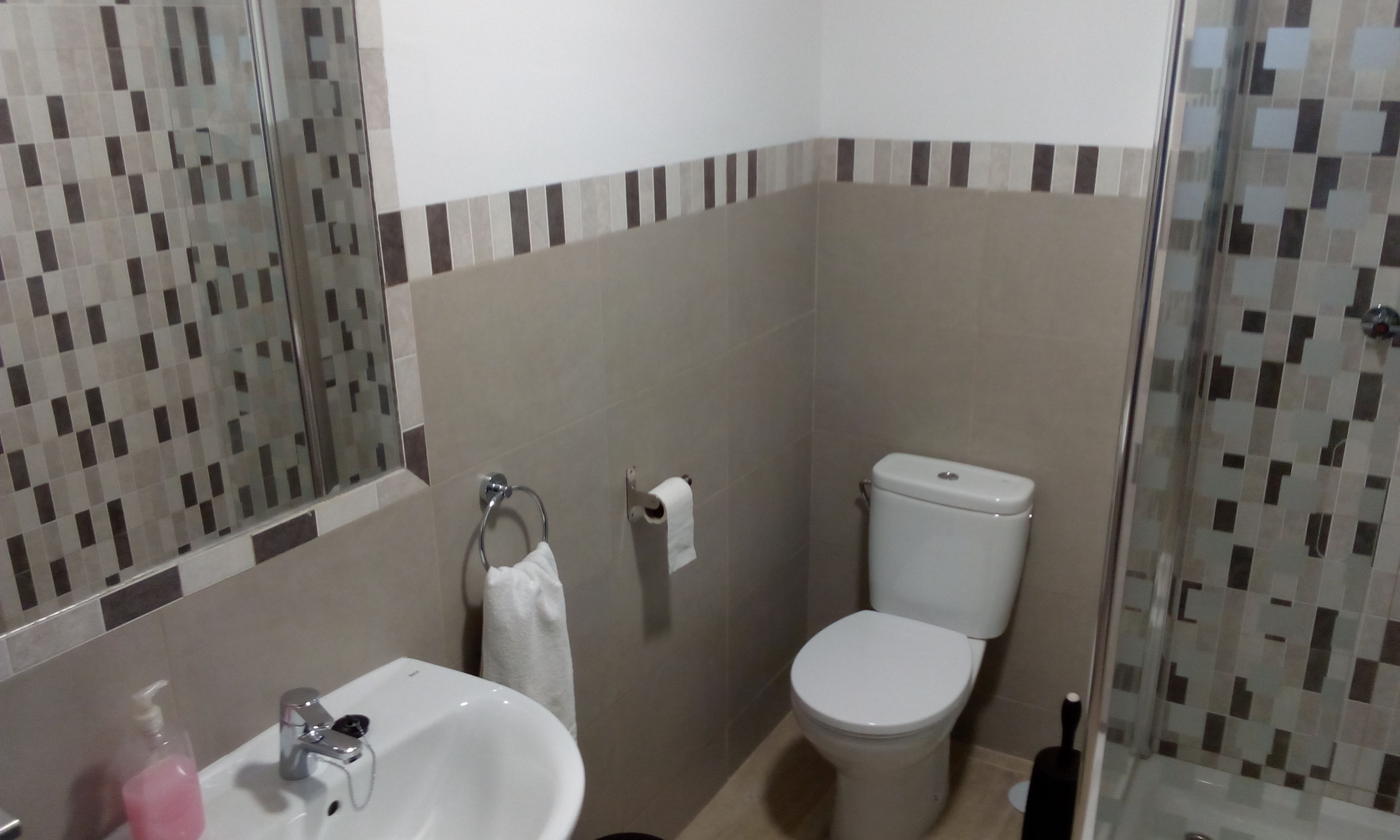 A bathroom with a sink, toilet, and glass shower enclosure.