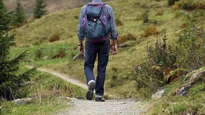 A person walking on a gravel path surrounded by greenery and hills. - Apartamentos Jucar (Tragacete)