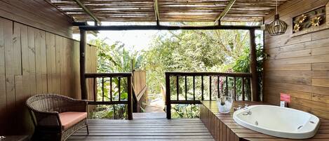 A wooden deck with a wicker chair and a bathtub.