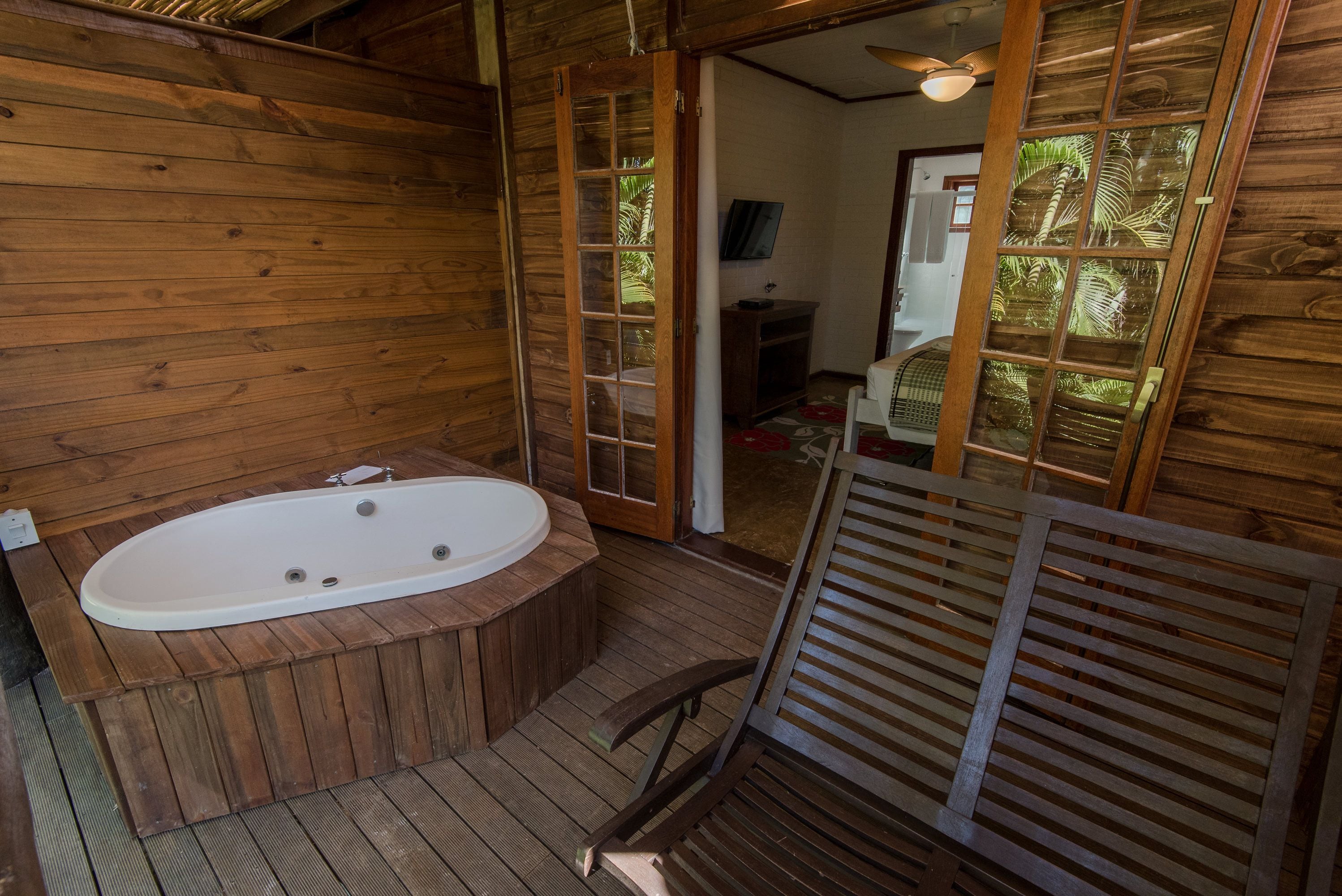 A wooden cabin with a wooden bathtub, a wooden chair, and a wooden floor.