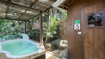 A wooden cabin with a hot tub, stone flooring, and a wooden fence.