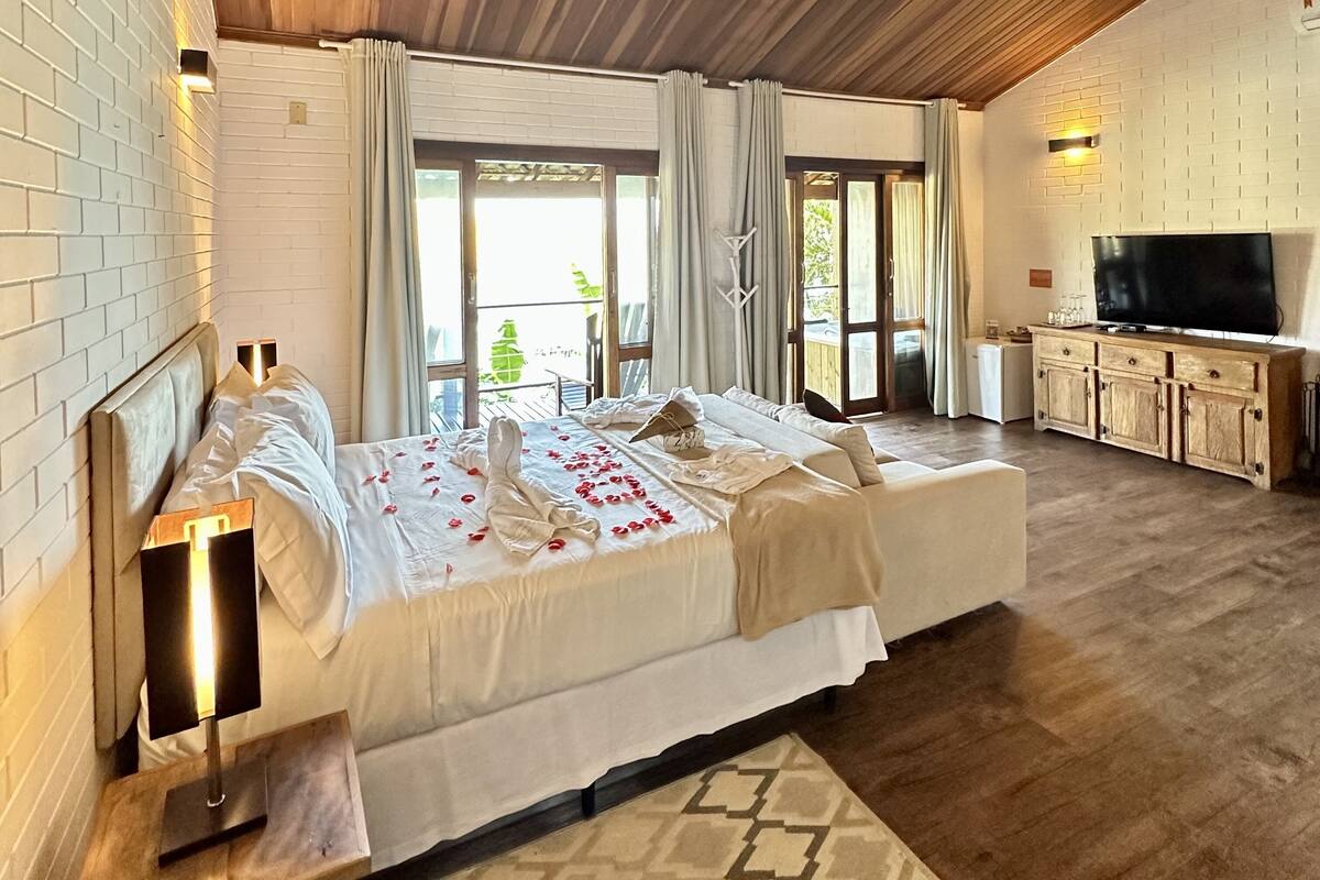 A spacious bedroom with a large bed, a television, and a wooden cabinet.