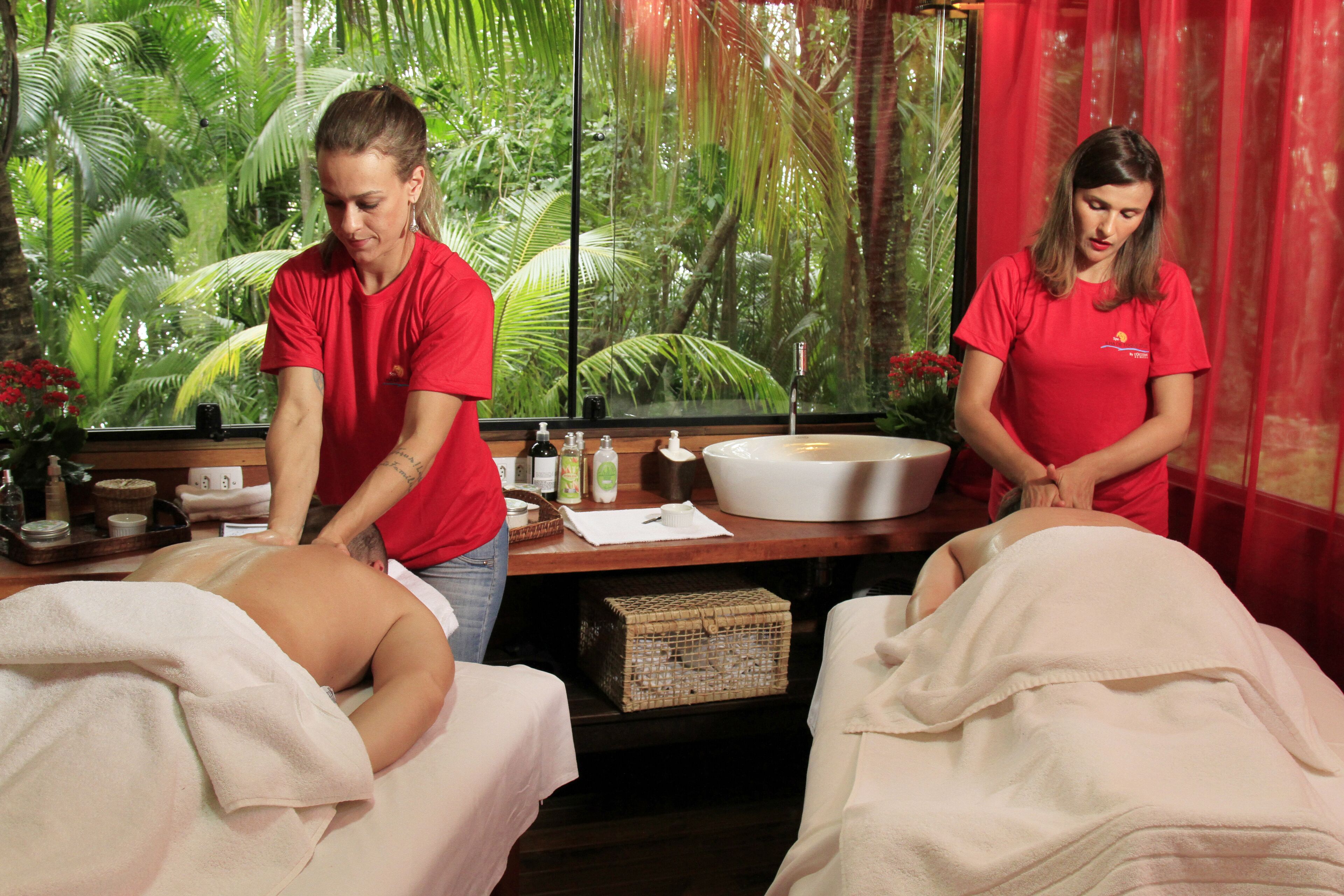 Un entorno de spa con dos camillas de masaje, un tazón grande y varias botellas, probablemente con aceites o lociones.