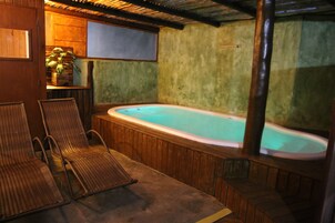 Un área de spa con un jacuzzi, sillas de mimbre y paredes de madera.