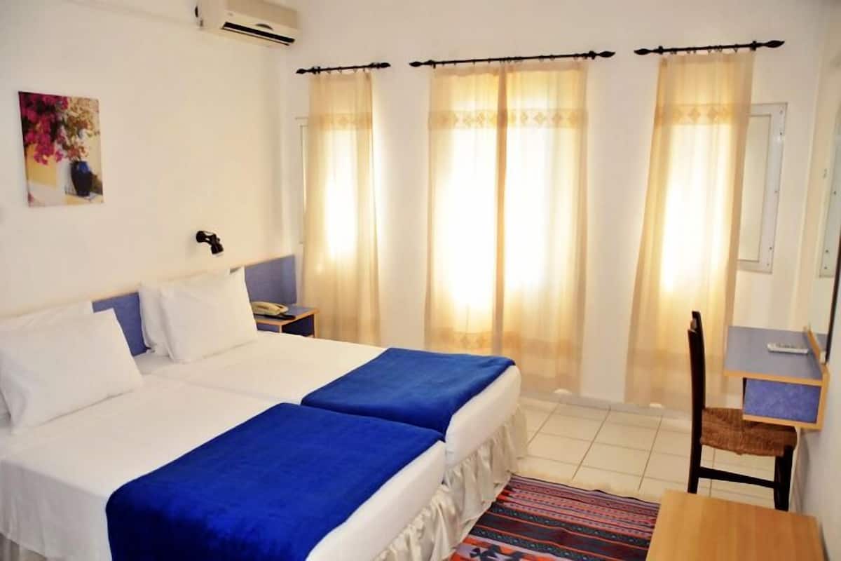A hotel room with two beds, a desk, and a chair.
