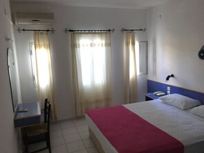 A hotel room with a bed, a desk, a chair, a bedside table with a lamp, and curtains. - Omar Hotel & Suites (Bodrum)