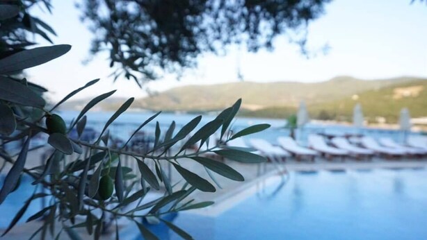 Ein Infinity-Pool mit Liegestühlen und Blick auf Hügel im Hintergrund.