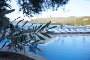An infinity pool with lounge chairs and a view of hills in the background. - Omar Hotel & Suites (Bodrum)