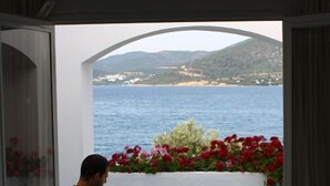 Ein Mann sitzt an einem Tisch mit Blick auf das Meer und die Berge.