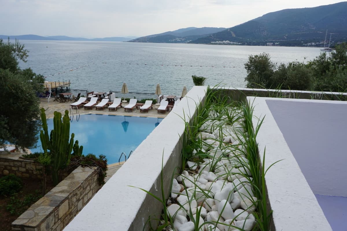 A pool with lounge chairs and a view of the sea.