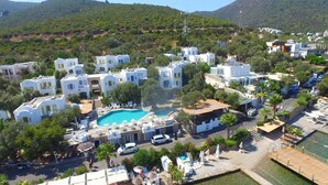 Ein Resort mit weißen Gebäuden, einem zentral gelegenen Schwimmbecken und einer bergigen Kulisse.