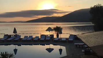 Una piscina al aire libre, sombrillas, sillones reclinables de piscina