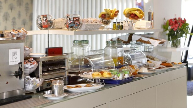 Un bufé con diversos alimentos, incluyendo pasteles y salsas, además de una estación de café.