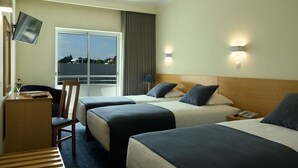Habitación de hotel con dos camas, un escritorio con silla, televisión y ventana con vistas.