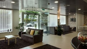 Un área de recepción moderna con un sofá, una mesa de centro y una puerta de vidrio que da al exterior.