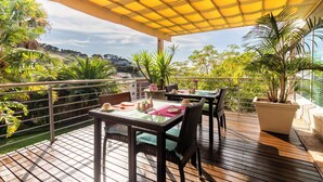 An outdoor patio with tables and chairs, surrounded by lush greenery and a scenic view. - Signal Hill Lodge (Cape Town)