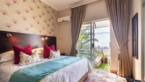 A hotel room with a large bed, a view of the outdoors, and an air conditioning unit on the wall. - Signal Hill Lodge (Cape Town)