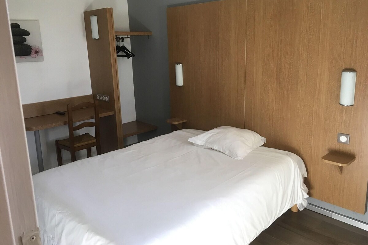 A bedroom with a bed, a desk, a chair, and a wardrobe.