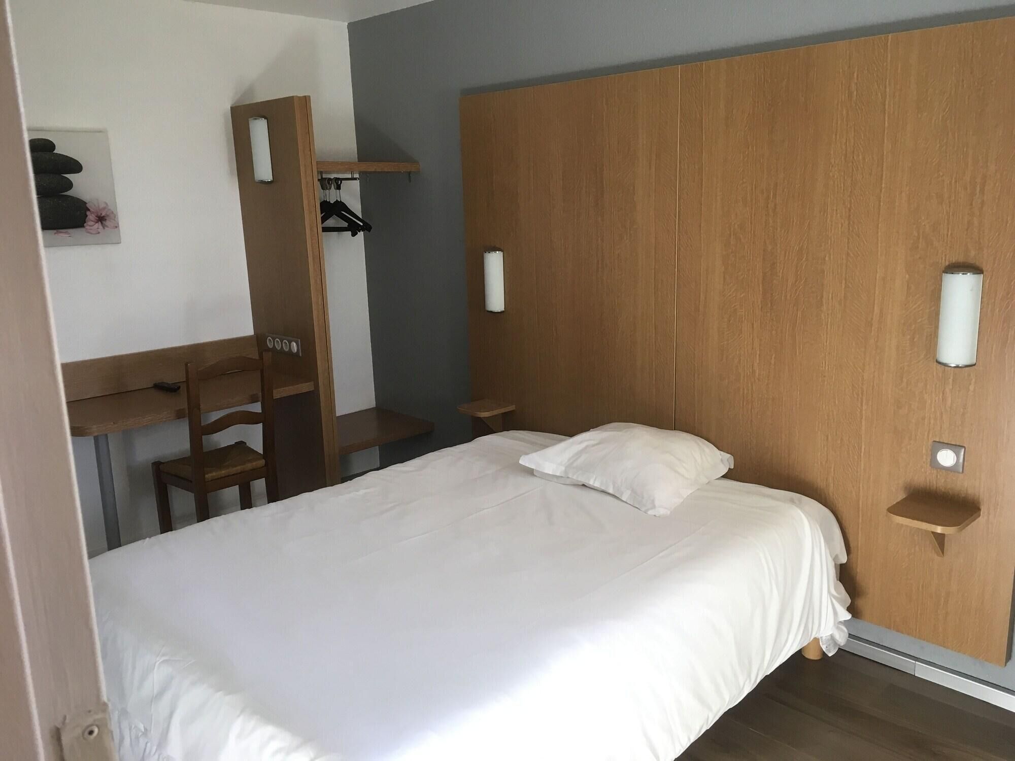 Une chambre à coucher avec un lit, un bureau, une chaise et une armoire.