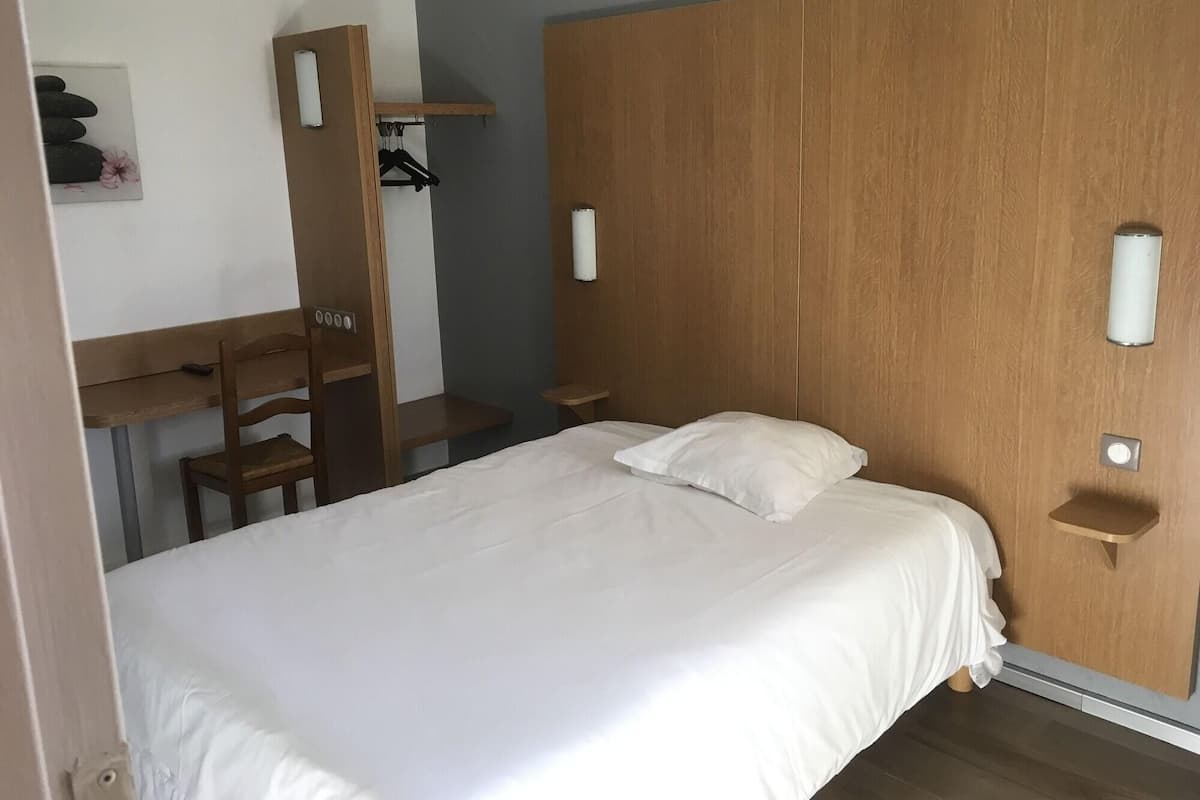 A bedroom with a bed, a desk, a chair, and a wardrobe.