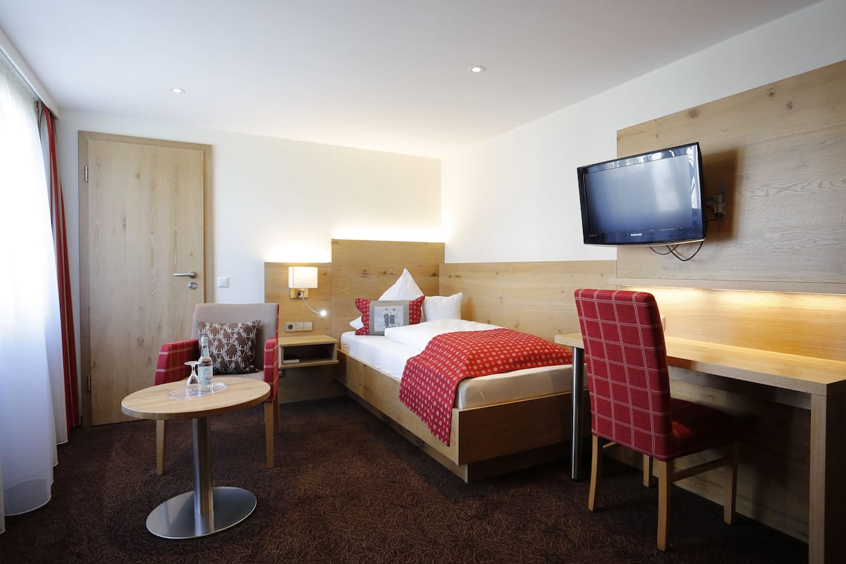 Una habitación de hotel con una cama, un escritorio, una silla, un televisor y una mesita.