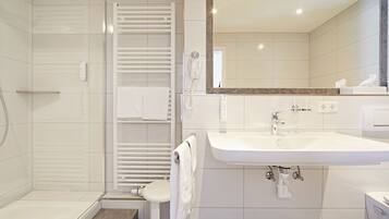 A modern bathroom with a walk-in shower, a toilet, a sink, and a mirror.