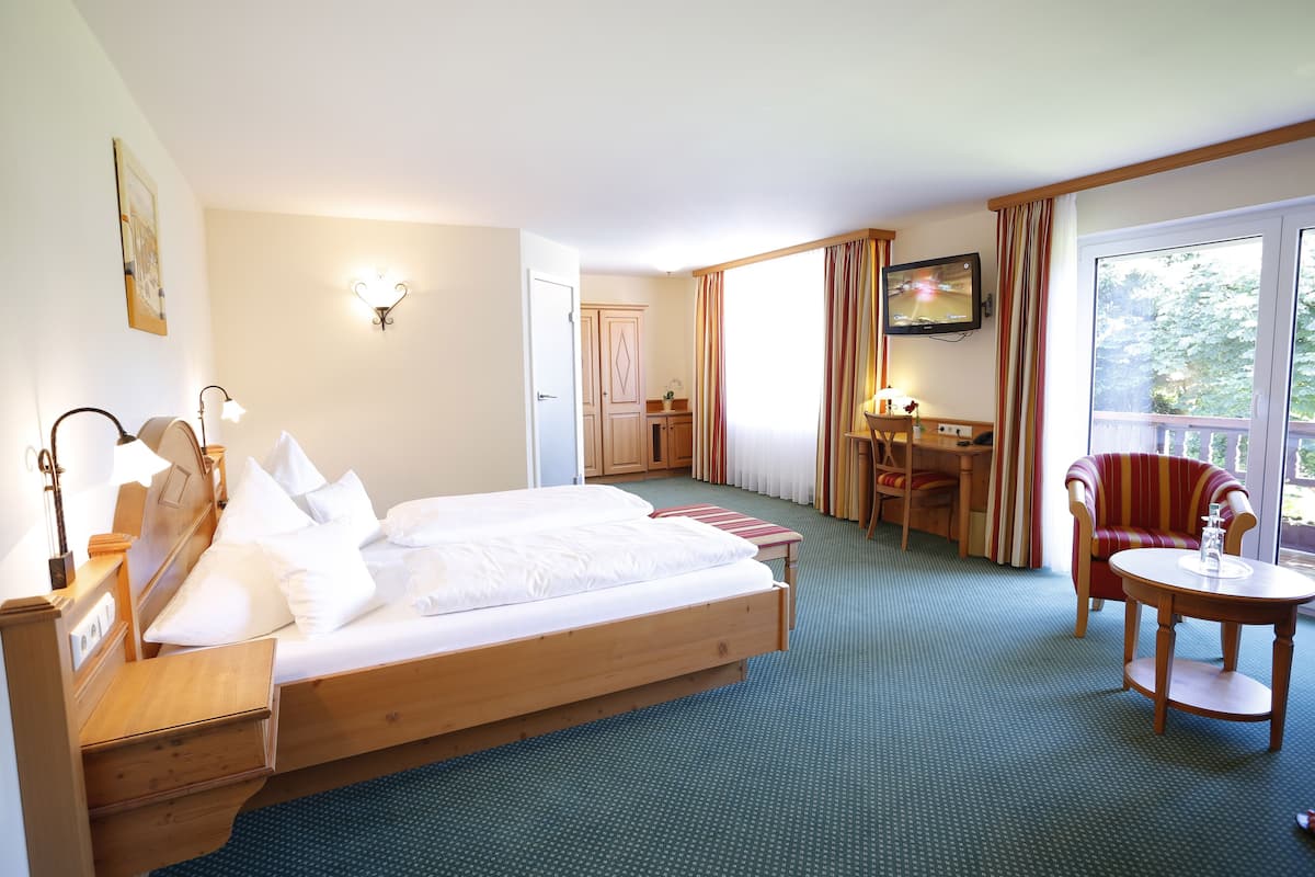 Una habitación de hotel con una cama grande, un escritorio, una silla y un televisor.