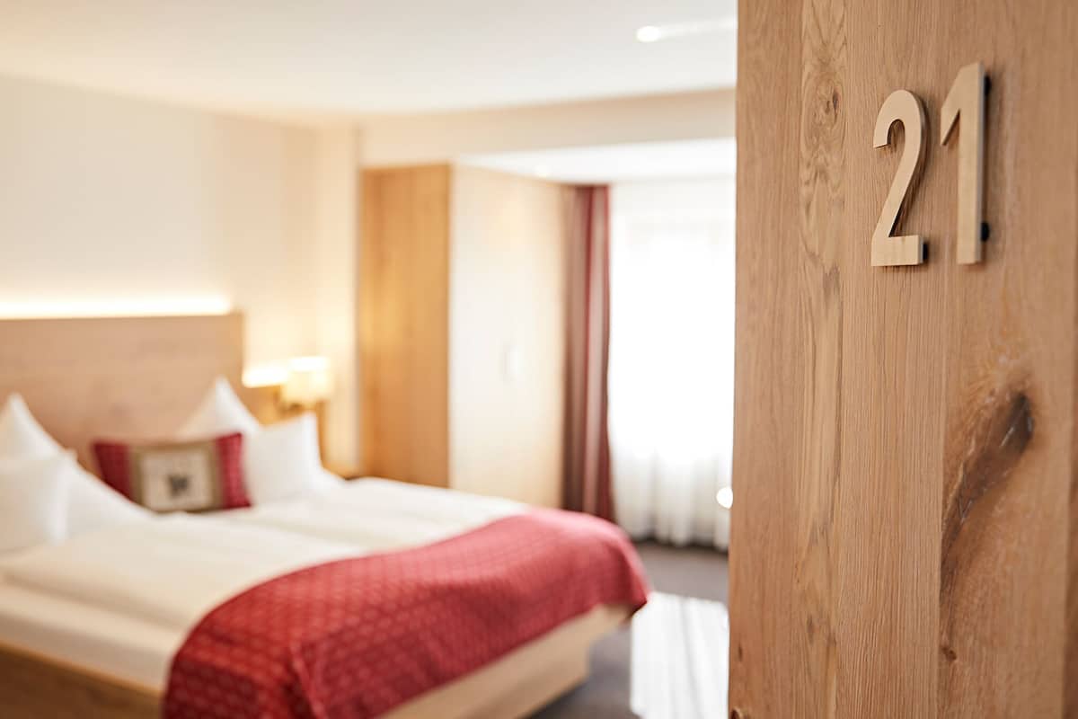 Habitación de hotel con una cama grande, un cabecero de madera y el número '21' en la pared.