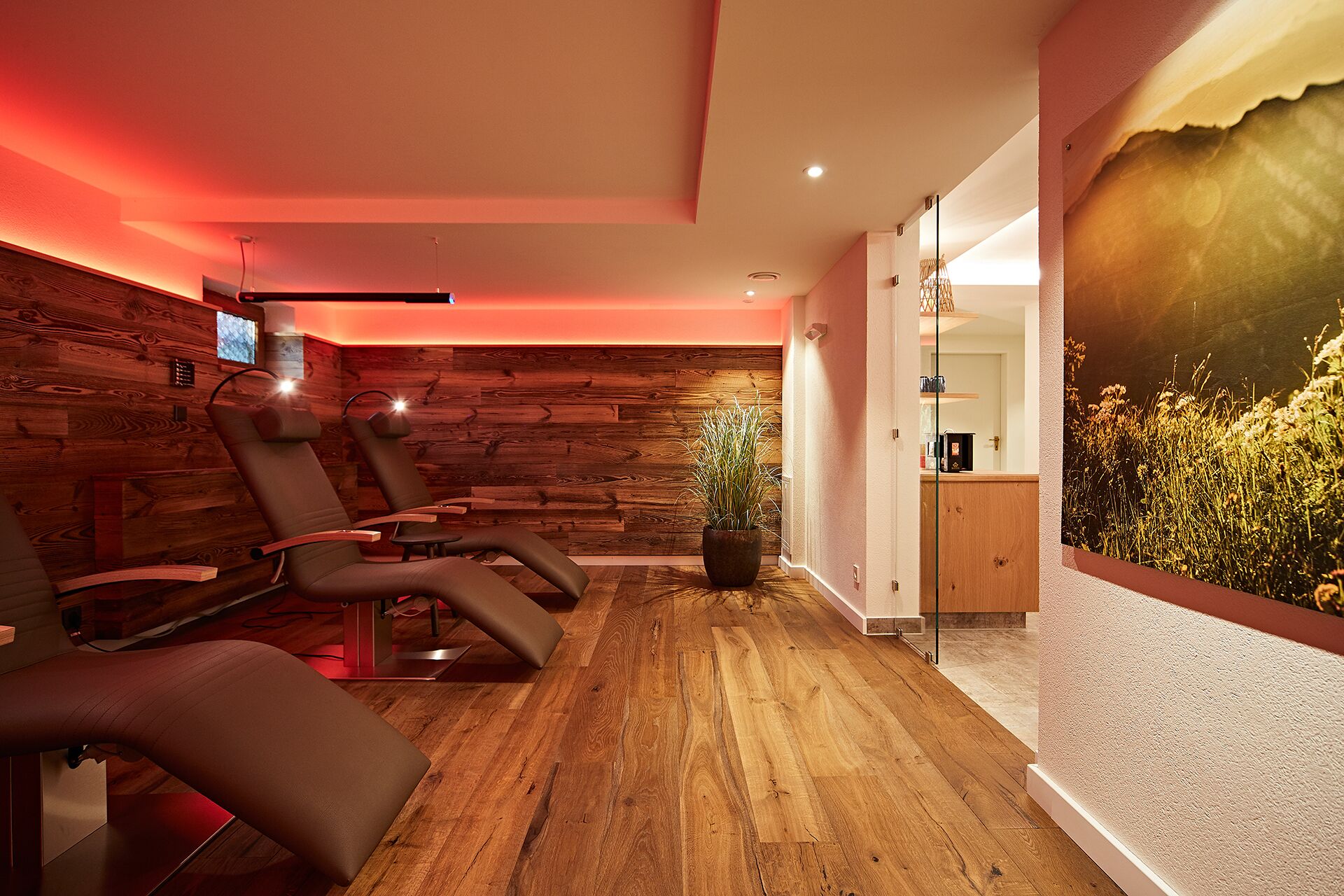 A room with wooden panel walls, a large window with a view of greenery, and a massage table.