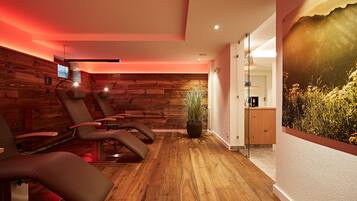 A room with wooden panel walls, a large window with a view of greenery, and a massage table.