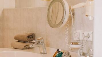 A bathroom with a sink, mirror, hairdryer, and towel rack.