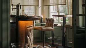 A modern kitchen with a bar area, bar stools, pendant lighting, and a view of the outdoors through large windows. - Hotel Restaurant Mühle (Binzen)