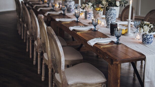 A long wooden dining table set with chairs, vases with flowers, and candles. - Hotel Restaurant Mühle (Binzen)