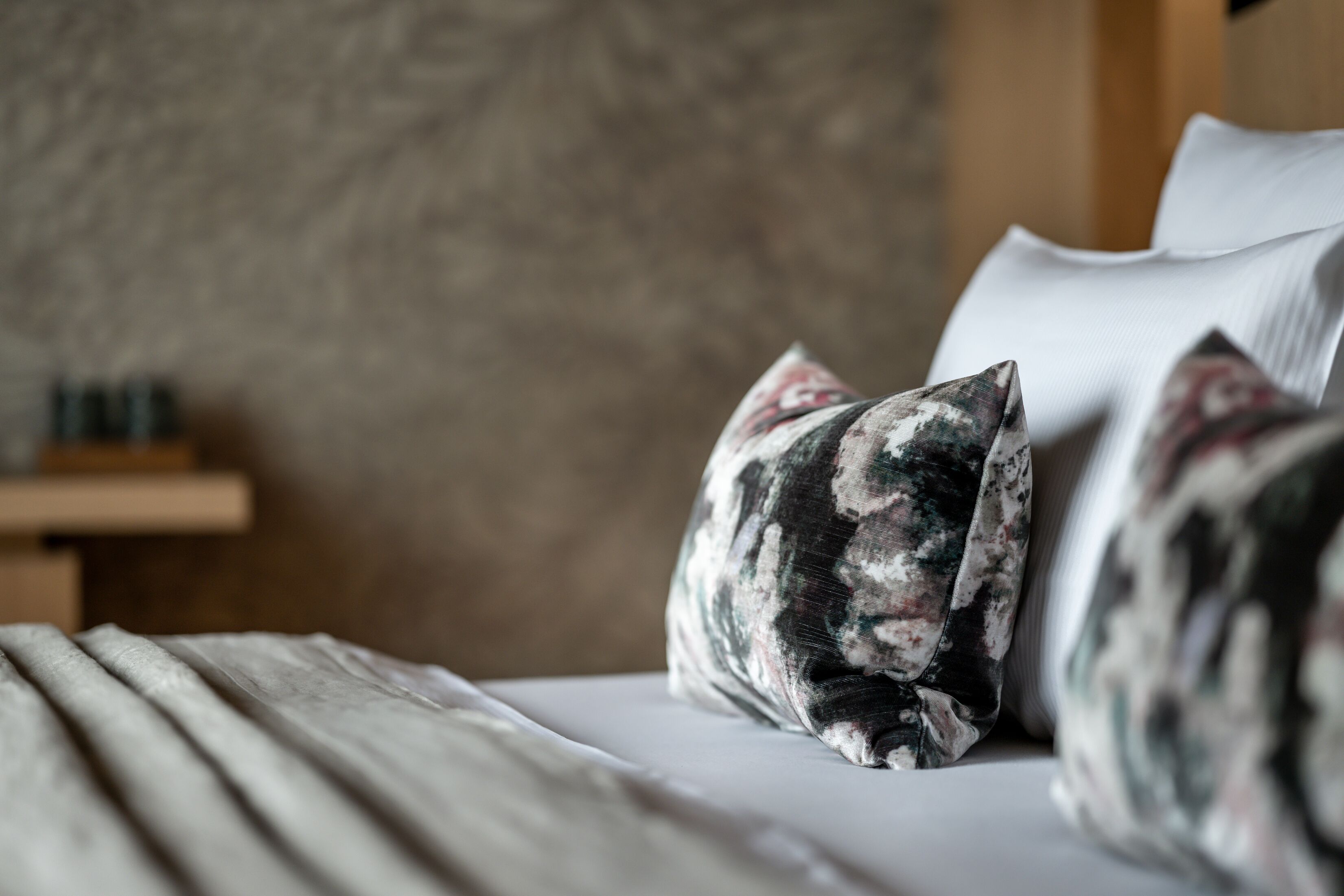 A bed with floral patterned pillows and a wooden headboard.