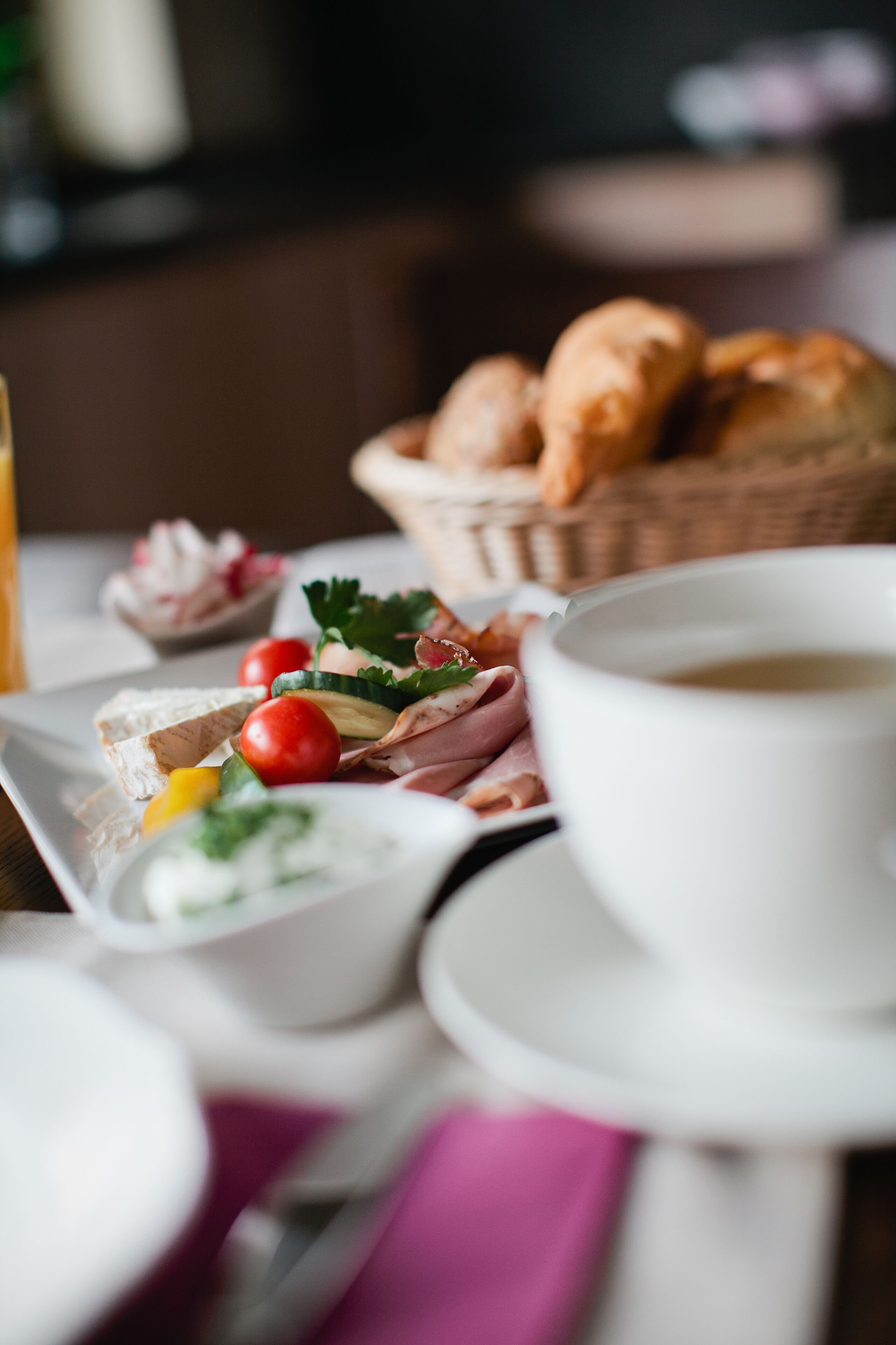 A breakfast setting with a plate of food, a cup of coffee, and a basket of bread.