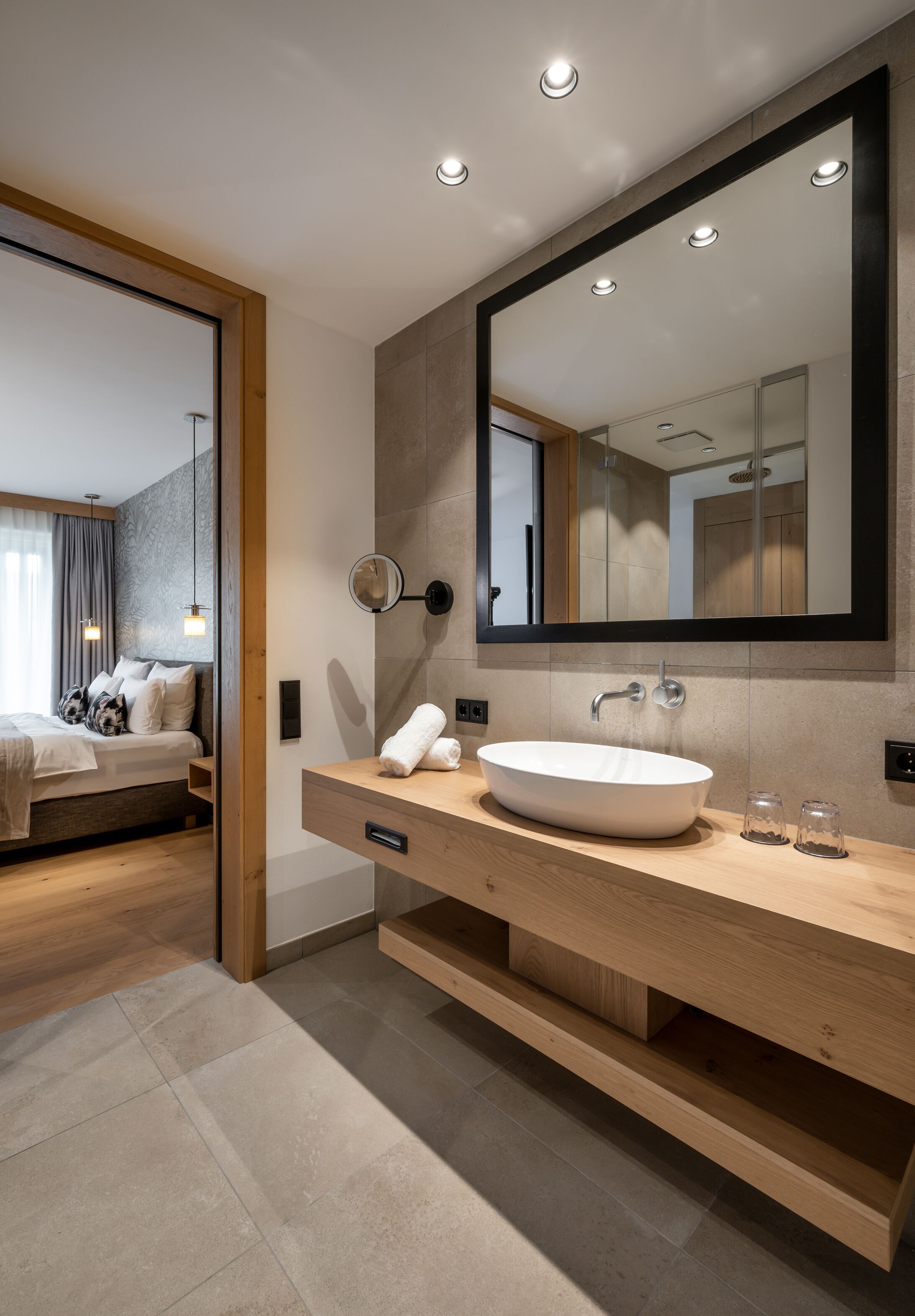 A modern bathroom with a large mirror, a wooden vanity, and a white sink.
